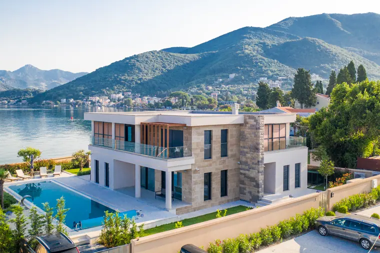 The seafront villa from above the water, its lap pool and terrace between the house and the sea wall.