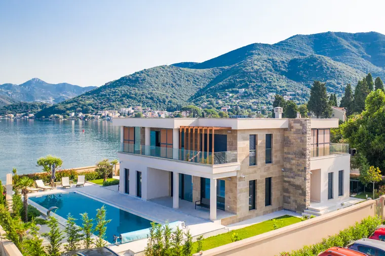 The villa and its pool set against the wooded ridge, the bay opening away to the north.