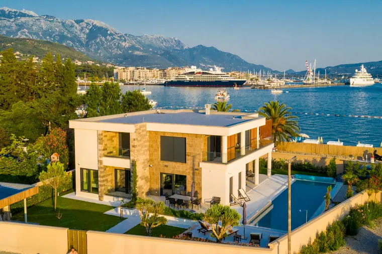 The villa seen from over the water, the pool and terrace stepping down towards the sea wall.