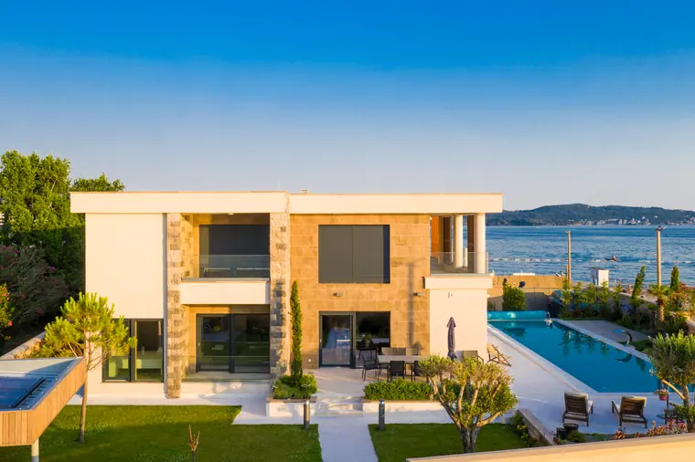 The seaward corner of the villa, with glass balustrades and a shaded loggia above the pool.