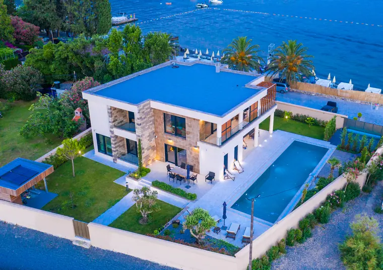 The villa from over the water, lit from within, above the pool terrace.