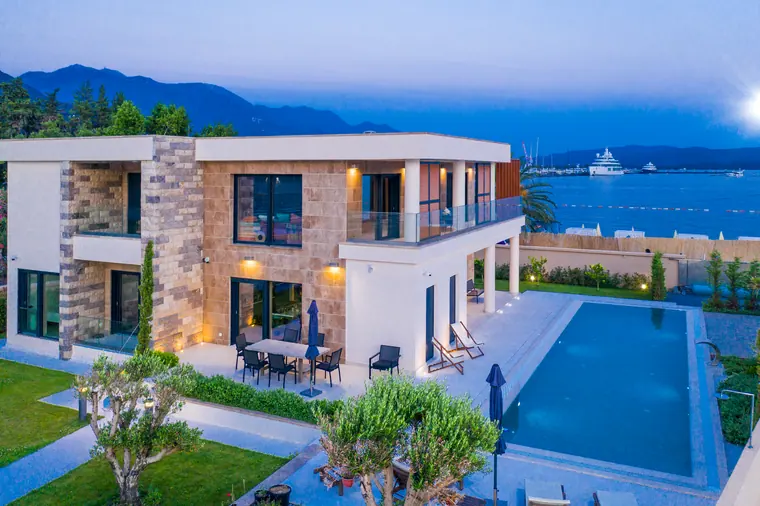 The pool terrace with loungers, the lit soffits of the loggia above.