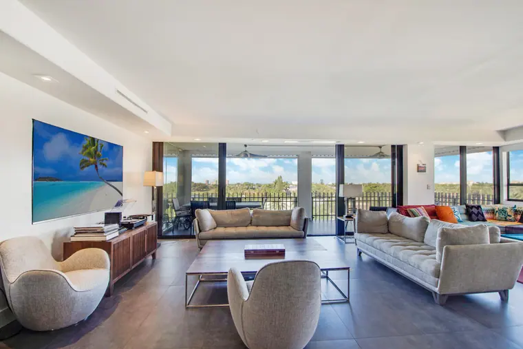 The living room from the terrace side, seating grouped beneath a continuous run of windows.