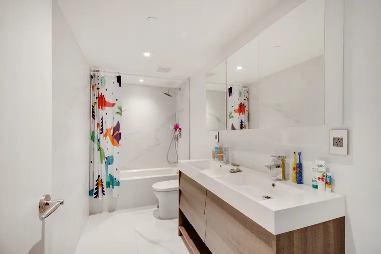 A bathroom in marble, with a wall-hung vanity and mirrored wall above.