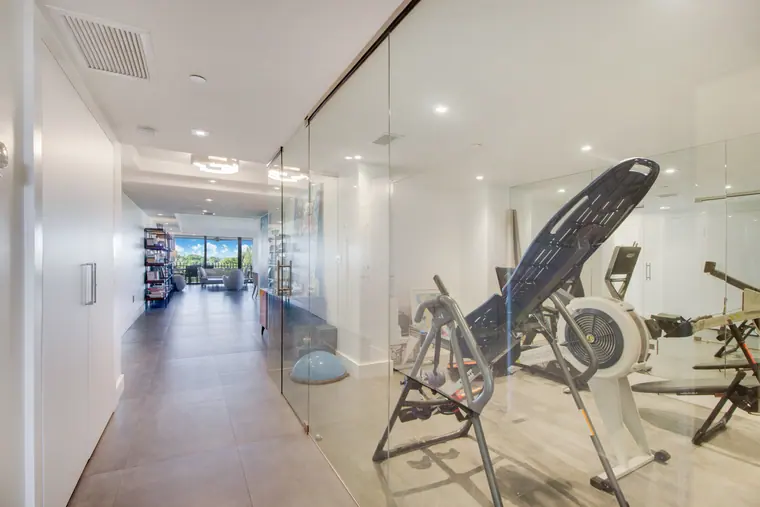 The corridor towards the gym, with a glazed partition and a long run of stone floor.
