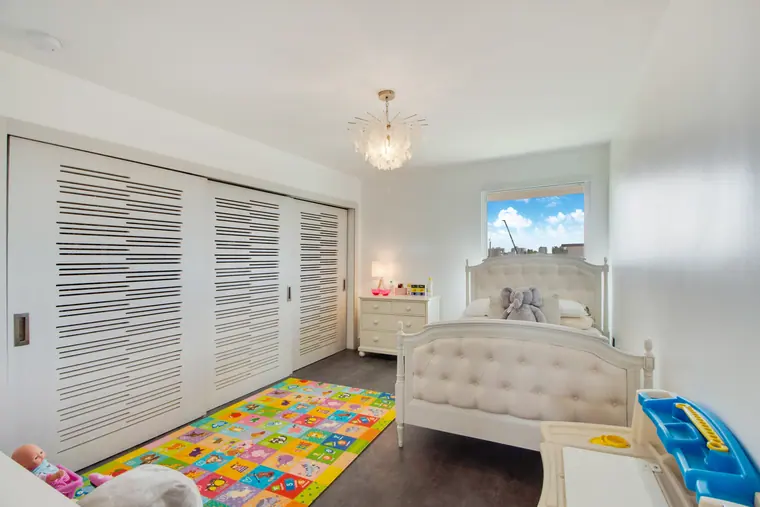A bedroom with full-height louvred wardrobe doors and a window along one wall.